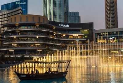 Dubai, United Arab Emirates - January 16, 2021: Dubai mall fountain show in front of Dubai mall shopping and leisure area surrounded and modern downtown buildings in the United Arab Emirates at blue hour